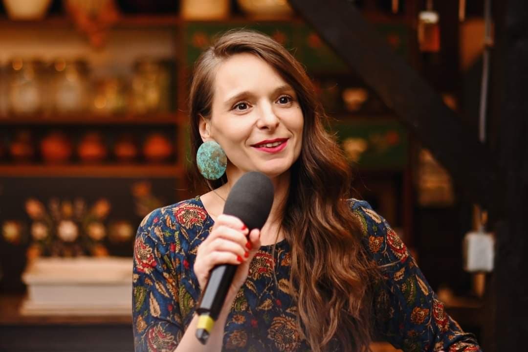 Alina Burlacu vorbind la microfon, zâmbind către participanți